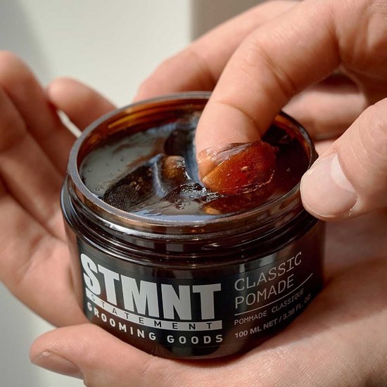 Handen pakken klassieke pomade uit een bruine pot. STMNT CLASSIC POMADE 100 ML / 3.38 FL. OZ.