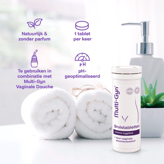 Wit flesje Multi-Gyn met paarse tekst, naast twee opgerolde witte handdoeken en een witte zeepdispenser.