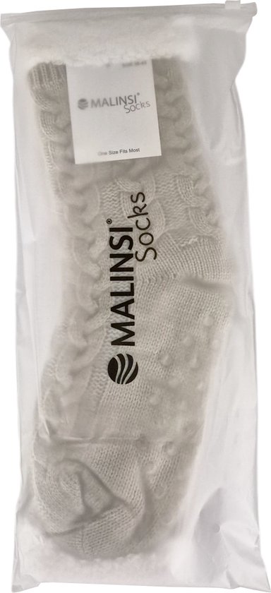 Een paar beige Malinsi huissokken verpakt in een doorzichtige plastic zak.