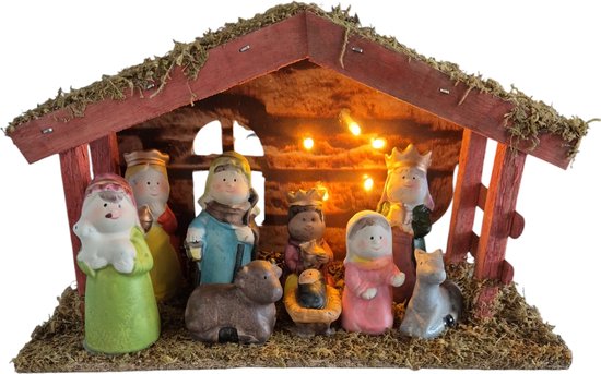 Kerststal met vrolijke beeldjes: Maria, Jozef, baby Jezus, schaap, ezel en koningen onder een rieten dak met lampjes.