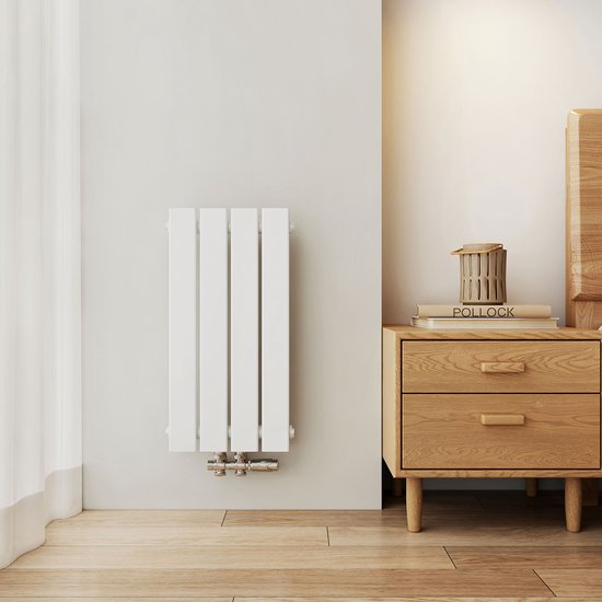 Witte verticale radiator met vier platte panelen, gemonteerd aan de muur naast een houten nachtkastje in een slaapkamer.