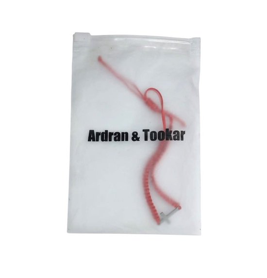 Een rode kruisarmband van Ardran & Tookar in een doorzichtig zakje.