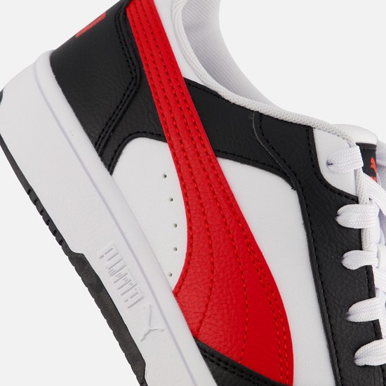 Close-up van de rode Puma-streep en zwarte leren details op een witte sneaker.