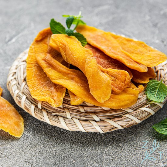 Gedroogde mango met muntblaadjes op een gevlochten onderzetter.