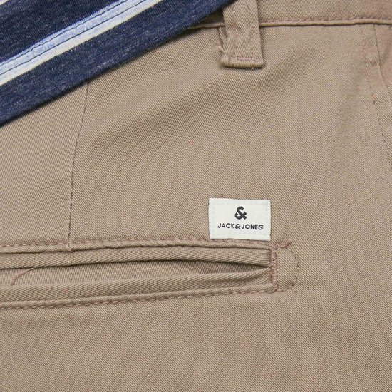 Detailopname van de achterzak van een beige chino broek met het Jack & Jones logo.