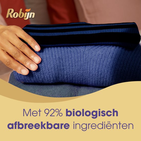 Gestapelde donkerblauwe kleding, met een hand erop. Tekst: Met 92% biologisch afbreekbare ingrediënten.
