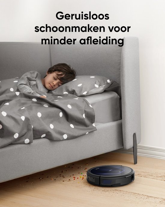 Zwarte eufy robotstofzuiger maakt geruisloos schoon terwijl een jongen slaapt in een bed met grijze stippen bed.