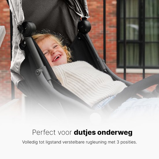 Lachend kind in een zwarte buggy met verstelbare rugleuning.
