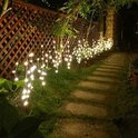 Buitenpad verlicht met bruine lichttakken met warmwitte LED's langs een houten hek.