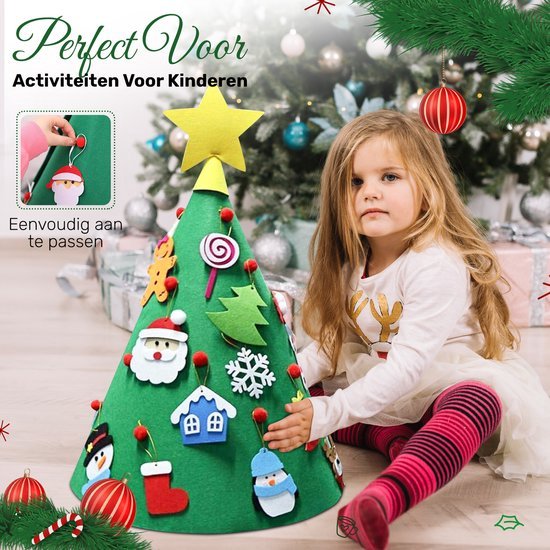 Een jong meisje zit naast een groene vilten kerstboom versierd met kerstornamenten.