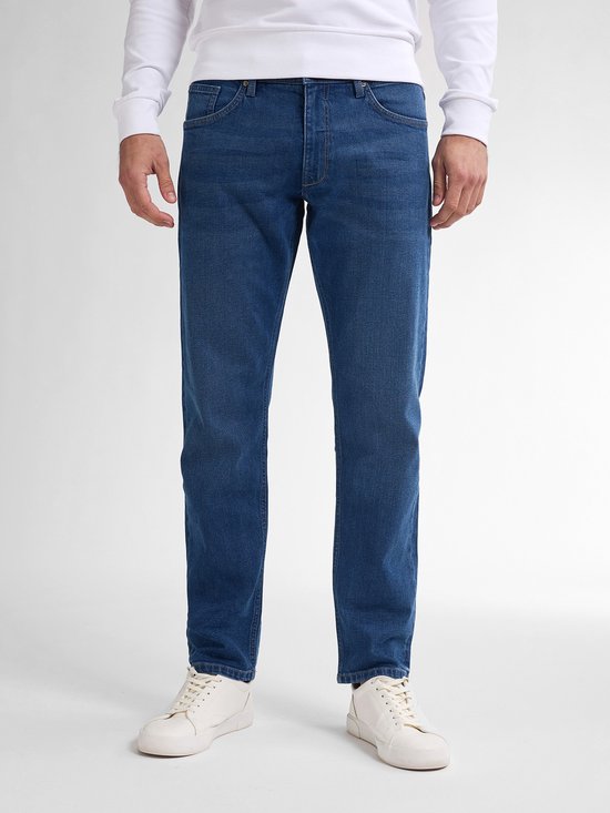 Vooraanzicht van een model in een wit shirt en blauwe tapered fit jeans.