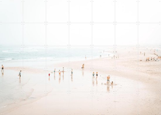 Une large plage avec beaucoup de monde, la mer et un léger brouillard.