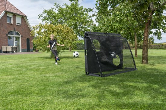 Jongen schiet voetbal bij een zwart EXIT voetbaldoel met ronde gaten.