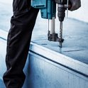 Gedetailleerde opname van een Bosch SDS plus-7X hamerboor die gebruikt wordt in beton met een boorhamer.