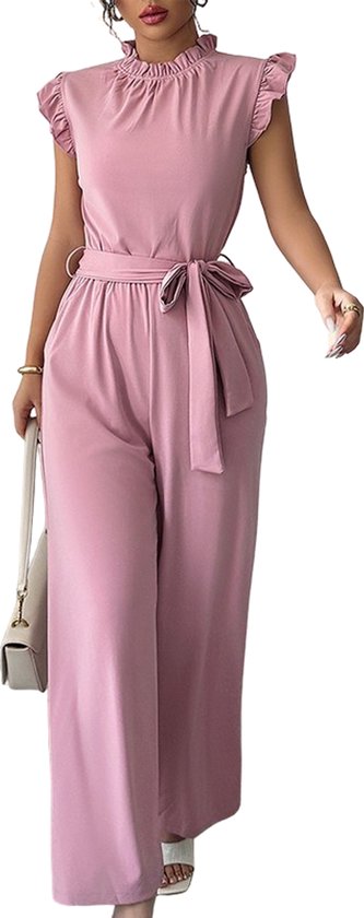 Roze jumpsuit met ruches aan de mouwen, opstaande kraag en strikceintuur. Gedragen met witte sandalen en witte tas.