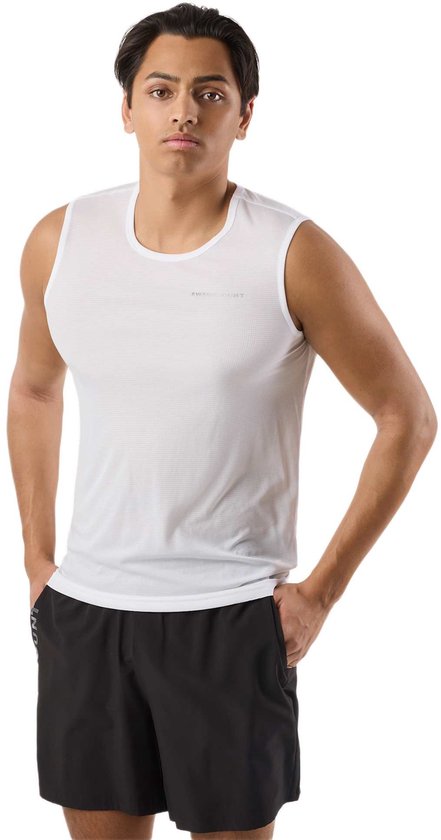 Homme poches mains, porte un débardeur blanc avec logo sur la poitrine et un short noir.