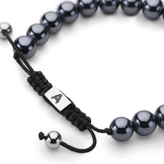 Zwart gevlochten koord van een armband, met een zilverkleurige 'A' bedel en donkergrijze hematiet kralen.