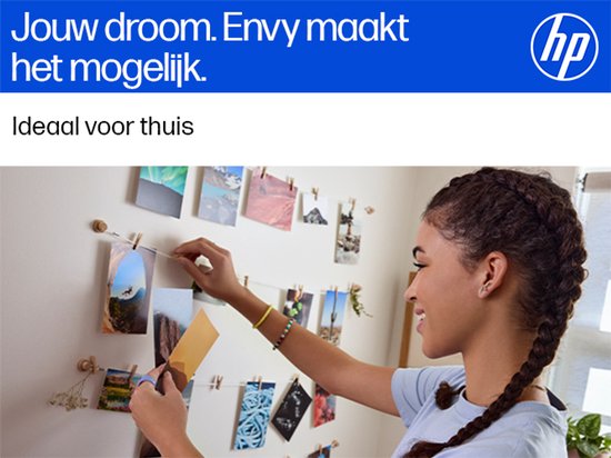 Jonge vrouw met vlecht met clipjes, hangt foto's op aan een muur.