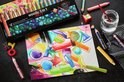 Een doos met 18 STABILO woody 3 in 1 ARTY potloden, naast een aquareltekening en losse potloden.