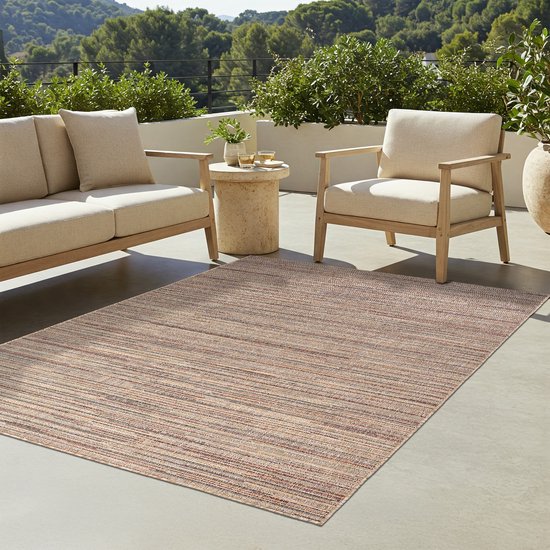 Tapis rayé beige sur un patio avec un canapé et des chaises beiges sous un ciel ensoleillé.