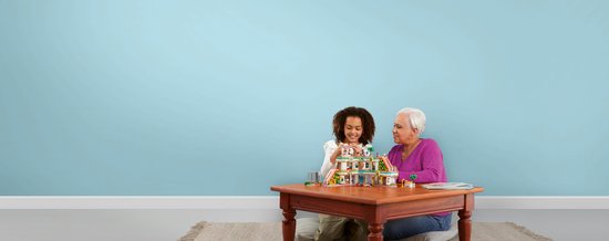 Une femme et une fille jouent avec un set LEGO Friends sur une table en bois.