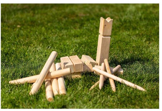 Houten Kubb spelonderdelen, waaronder pionnen en een koning, verspreid op groen gras.