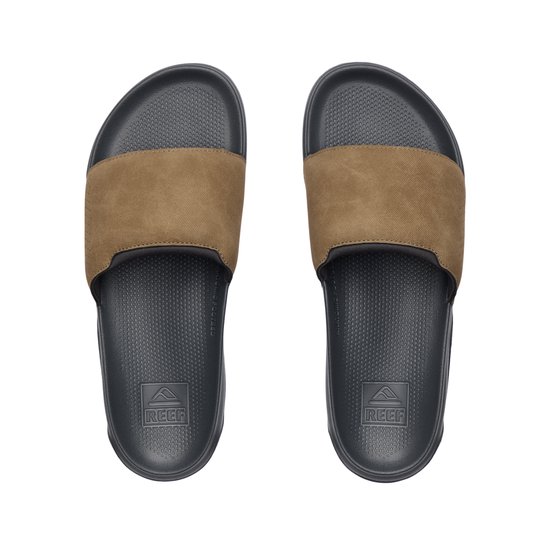Een paar grijze Reef slippers met camelkleurige band, gezien van bovenaf.