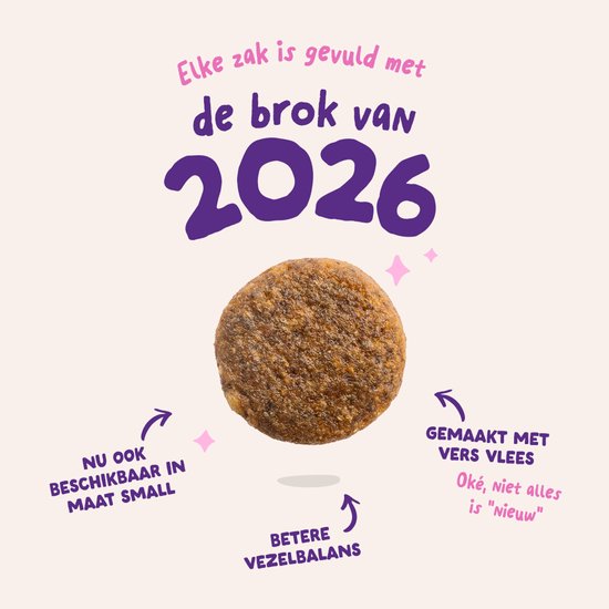 Een close-up van hondenbrokjes op een roze achtergrond. De tekst "Elke zak is gevuld met de brok van 2026" staat erboven.