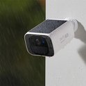 Witte camera met zwart zonnepaneel, besprenkeld met water. 'Holds Up in Any Weather'.