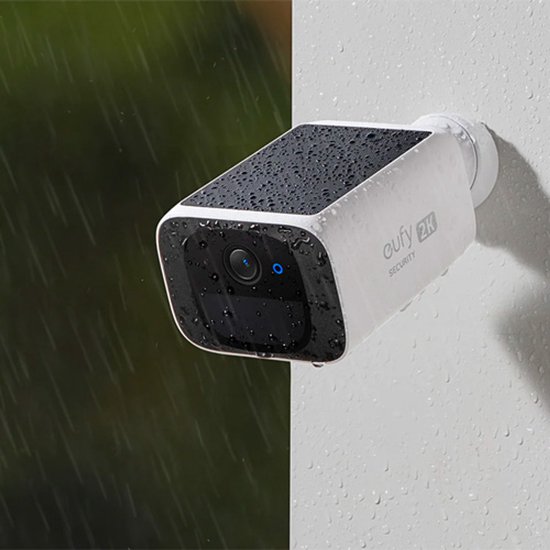 Witte camera met zwart zonnepaneel, besprenkeld met water. 'Holds Up in Any Weather'.