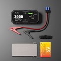 Zwarte jumpstarter 'AutoXtreme 3000' met rode en zwarte klemmen, kabel en opbergzak op grijze achtergrond.