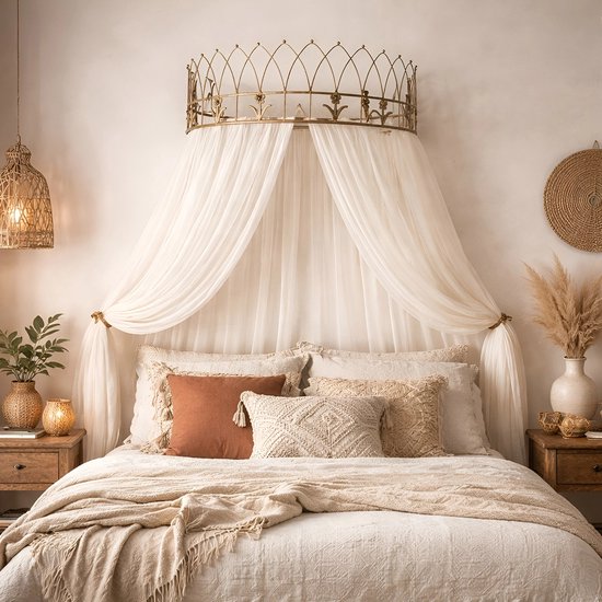 Gouden metalen kroon boven een hemel van witte stof boven een bed met veel kussens.