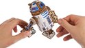 Handen monteren een arm van de houten R2-D2 modelbouwkit.