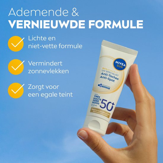 Hand met tube Nivea Sun UV Specialist Anti-Taches SPF 50+ tegen blauwe hemel. Ademende en vernieuwde formule.