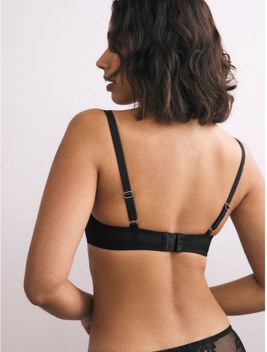 Model op de rug gezien, draagt zwarte push-up beha met bandjes.