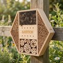 Hexagonaal insectenhotel van hout met verschillende secties: bamboestokken, dennenappels, boorblokken en 'BASTION' gegraveerd.