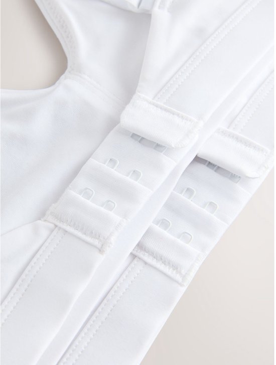Sluiting van witte bralette met haakjes en oogjes.