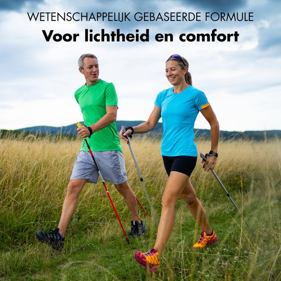 Man en vrouw in sportkleding, lachend tijdens het nordic walking in een veld met hoog gras.