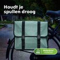 Mintgroene dubbele fietstas op een fiets in de regen. De tas is waterdicht.