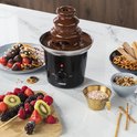 Zwarte Princess chocoladefontein met 3 lagen, omringd door fruit, koekjes en snoepgoed.