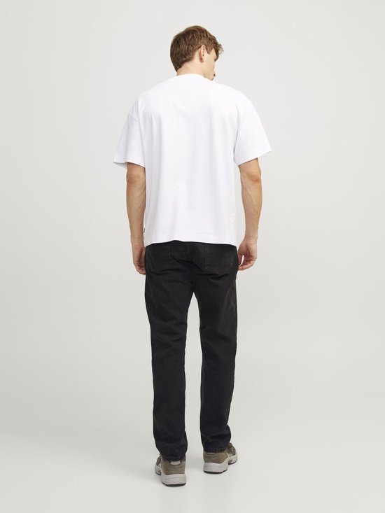 Man van achteren gezien in een losvallend wit T-shirt en zwarte jeans.