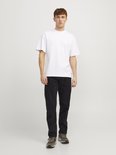 Man draagt wit oversized t-shirt en zwarte jeans.