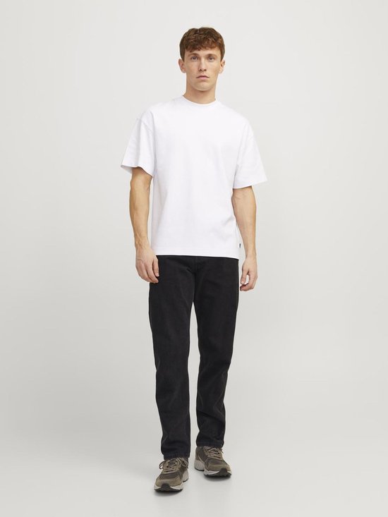 Man draagt wit oversized t-shirt en zwarte jeans.
