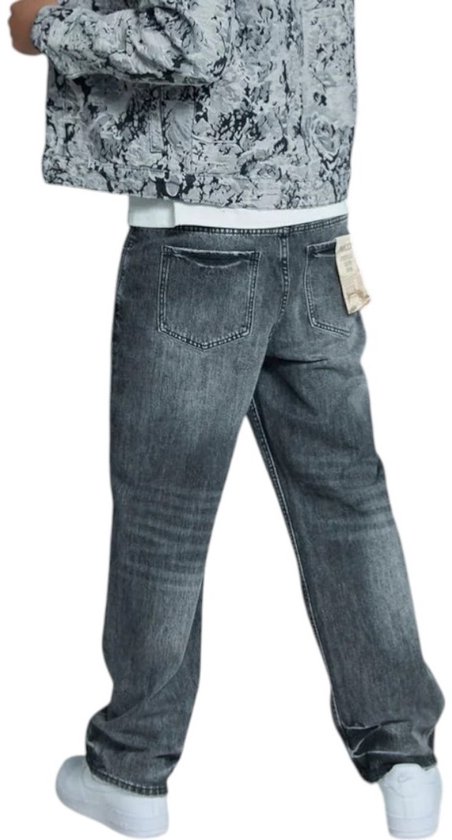 Man met grijze jeans en een grijs jack met bloemenprint, van achteren gezien.