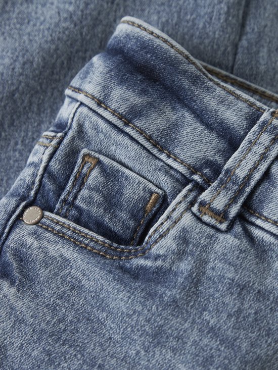 Detail van de tailleband en zakken van een blauwe skinny jeans.