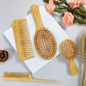Set van bamboe haarverzorgingsproducten: een grote kam, een ovale borstel, een kleine borstel en een puntkam.
