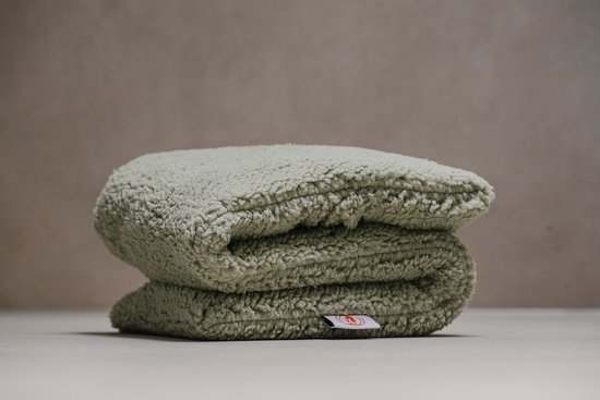 Een opgevouwen, olijfgroen, pluche kersenpitkussen met een label van Loeiwarm.