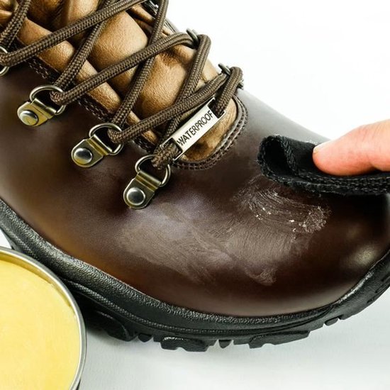 Bruine leren wandelschoen met bruine veters, waterdruppels en een hand die de schoen poetst met een zwart doekje.