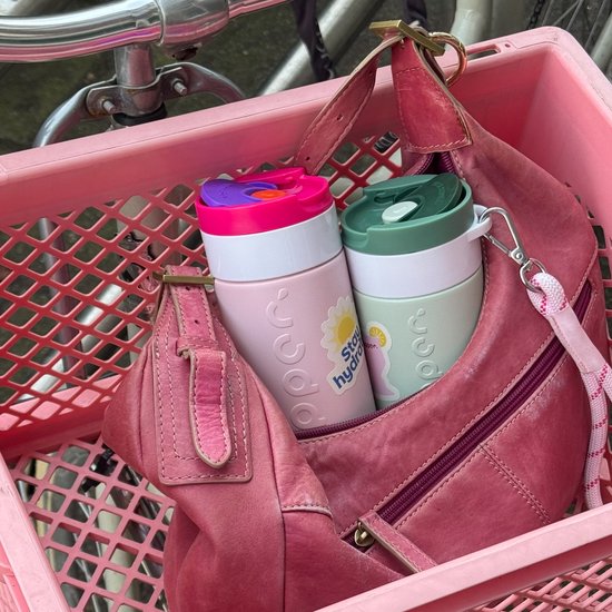 Roze fietsmand met twee Dopper Travel Mugs, één lichtroze en één lichtgroen, en een roze tas.