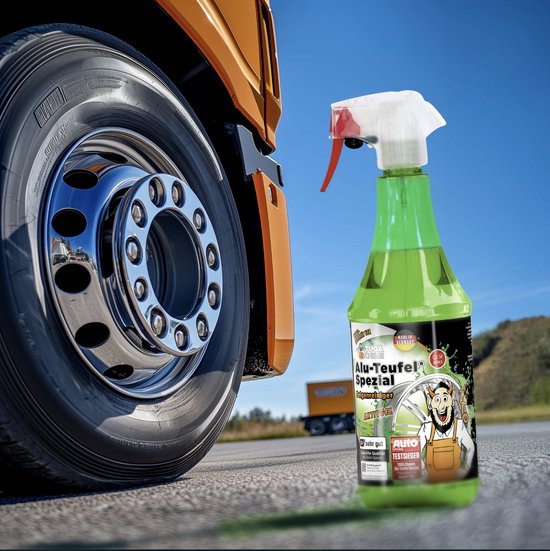 Groene ALU-Teufel spuitfles naast een glimmende vrachtwagen velg op een asfalt weg. Op de achtergrond een gele kiepwagen.
